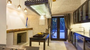 A modern kitchen with a stone backsplash, a dining area with a table and chairs, and a view of the outdoors through a glass door. - Villa in Santa Eulària Des Riu with 4 bedrooms sleeps 8 (Santa Eulària Des Riu)