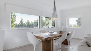 Een moderne eethoek met een houten tafel, witte stoelen en een kroonluchter.