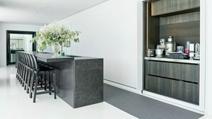Une cuisine moderne avec un îlot en marbre, des chaises noires et un meuble en bois.
