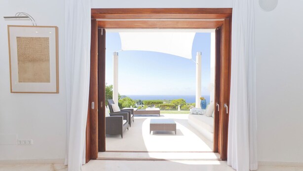 Habitación con vista al mar, un cuadro en la pared y una zona de estar con mesa y sillas.