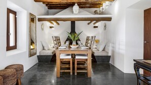 Comedor con mesa de madera preparada para cuatro personas, rodeado de asientos acolchados.