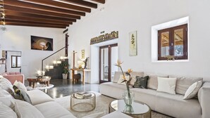 Un salón amplio con un sofá beige grande, una mesa de centro y una escalera que sube a un nivel superior.