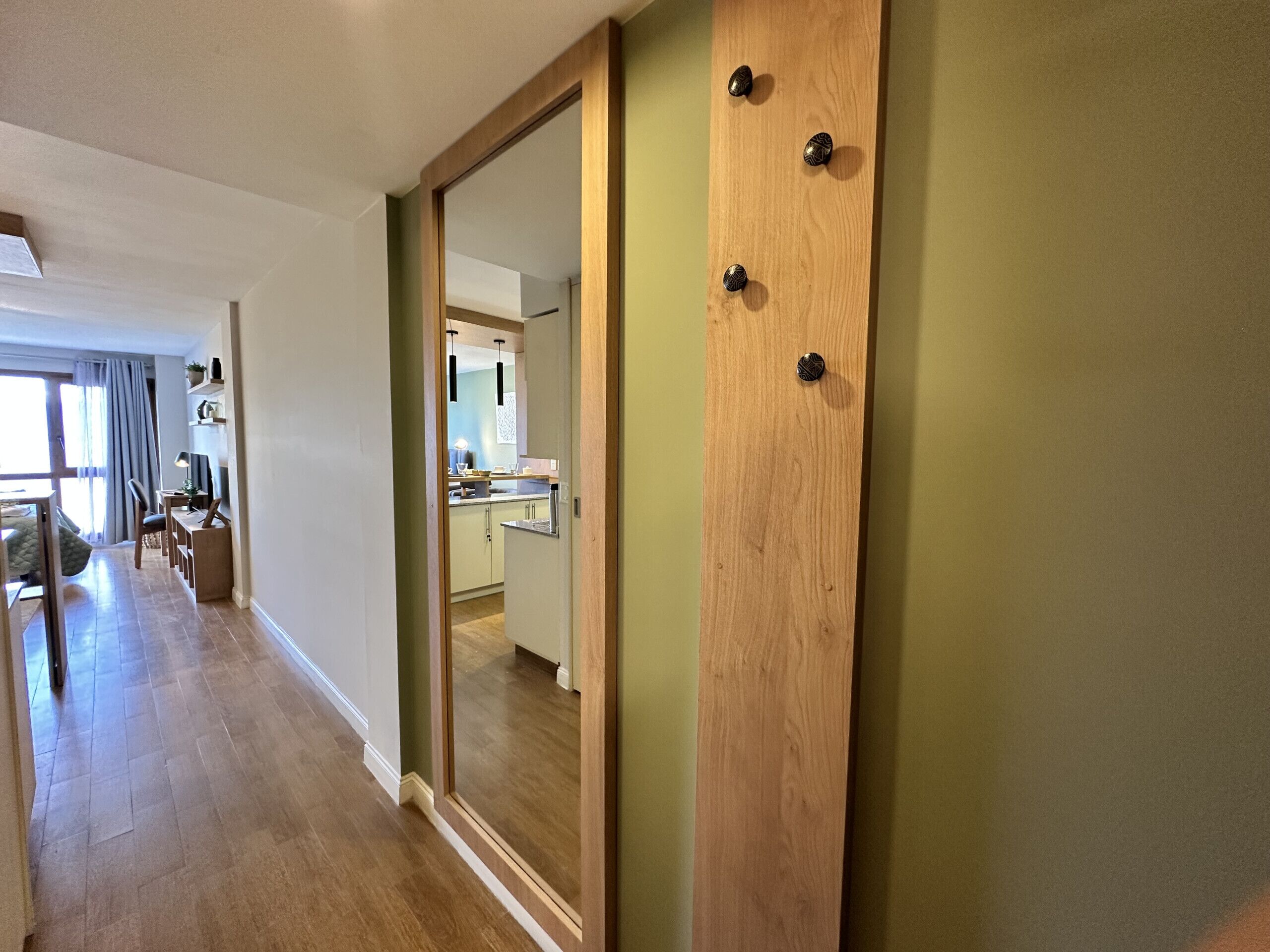 A modern interior with a wooden door, a kitchen area, and a dining space with a view to the outside.