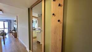 A modern interior with a wooden door, a kitchen area, and a dining space with a view to the outside.