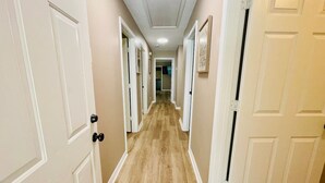 Un couloir avec des portes blanches et des murs de couleur beige.