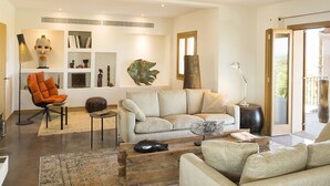Una sala de estar moderna con un sofá, sillones, una mesa de centro y una estantería.