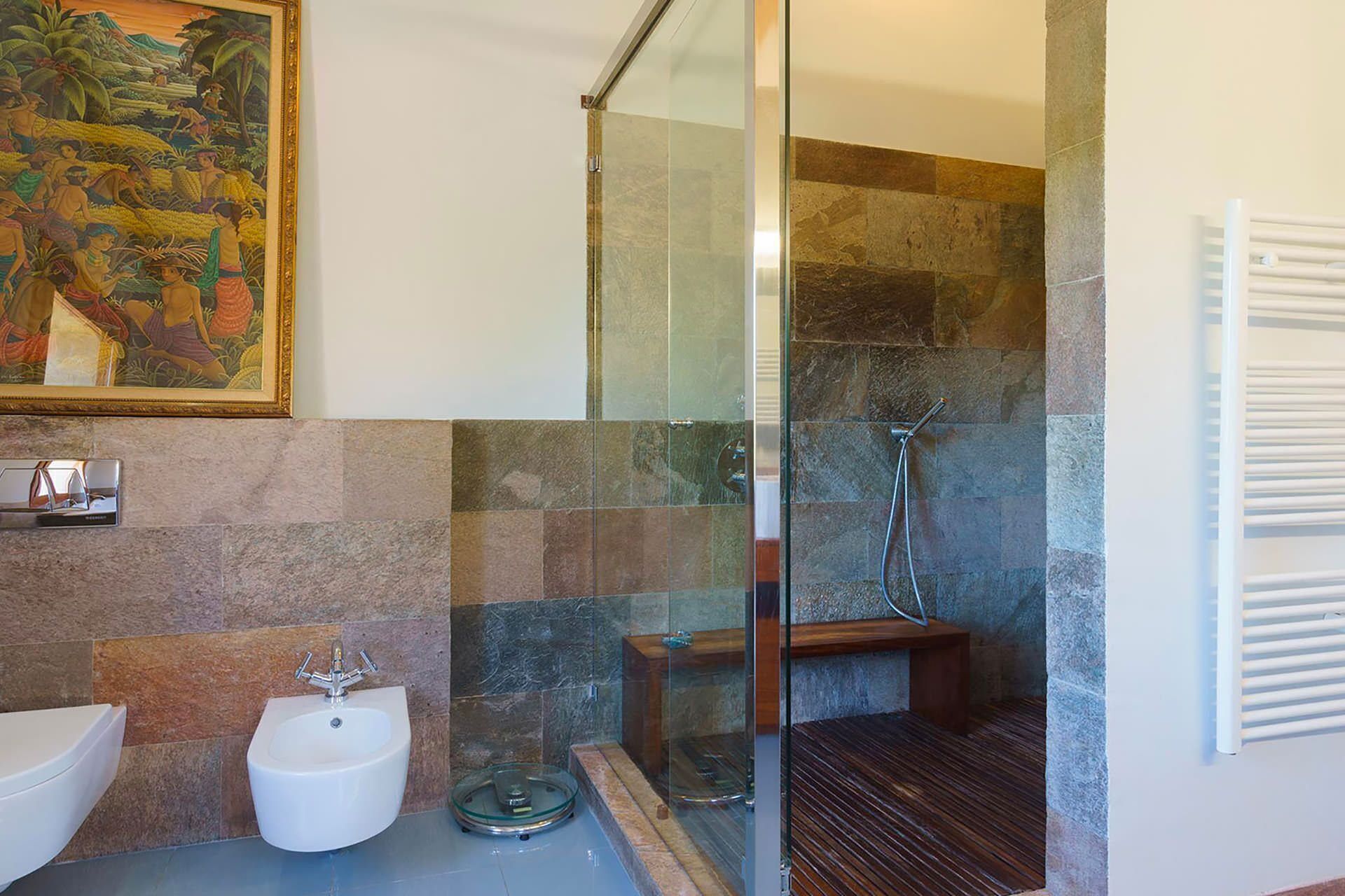A bathroom with a glass-enclosed shower, a bidet, and a sink.
