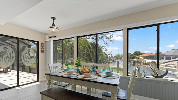A dining area with a table set for four, large windows, and a view of the outdoors. - GameRoom | Canal | Large Dock | Pool | Pets OK! 6 beds (Palm Coast)