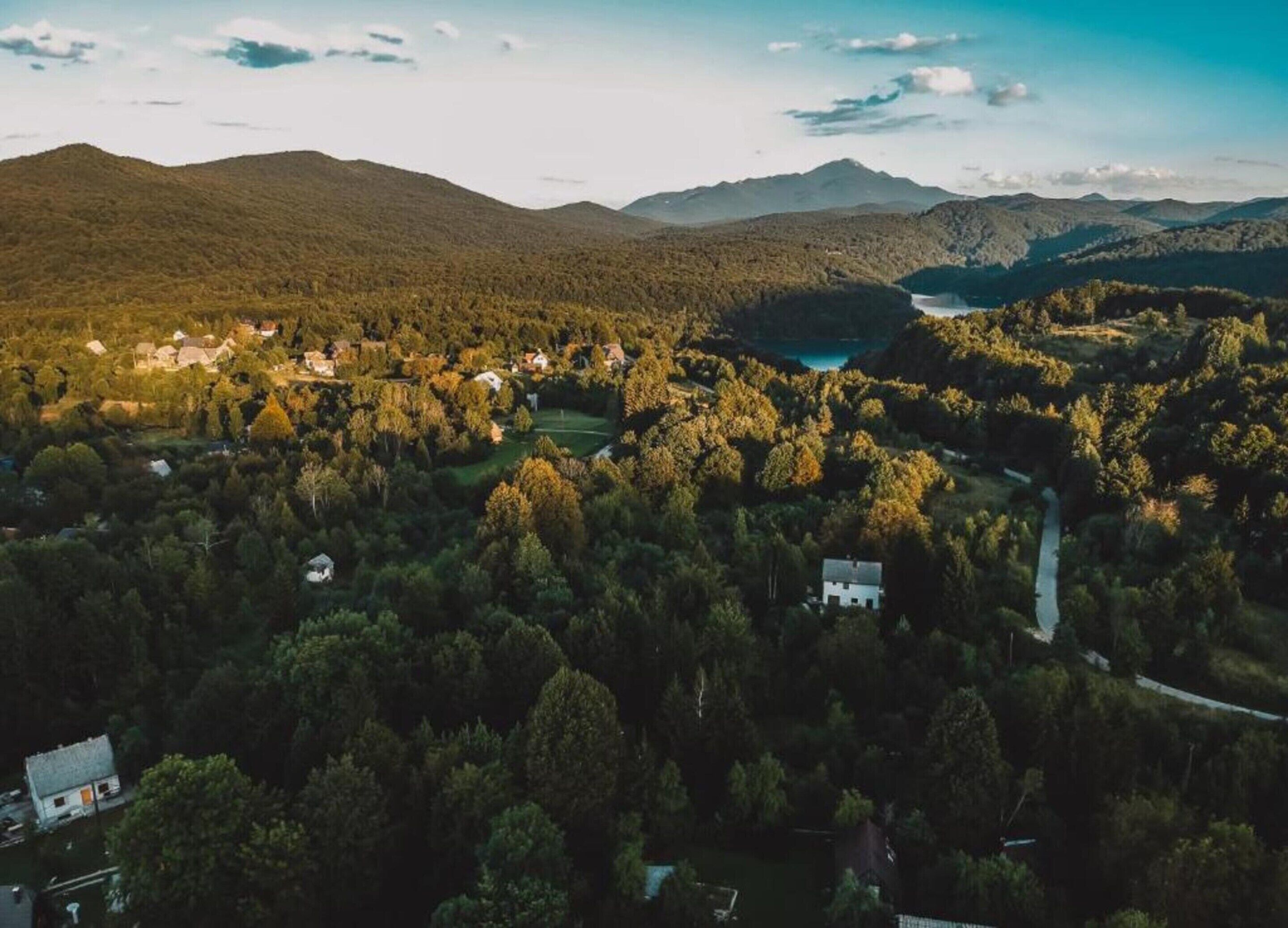 Vista aérea de uma área residencial com casas, um lago e colinas ao redor.