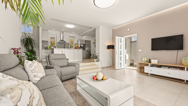 A modern living room with a grey sofa, a glass coffee table, and a flat-screen TV. - Modern Villa Novtek with Pool and Sea View (Diminići)
