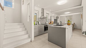 A modern kitchen with a central island, built-in oven, and a large window. - Modern Villa Novtek with Pool and Sea View (Diminići)