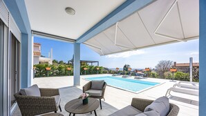 A poolside area with wicker furniture, a pool, and a view of the sea. - Modern Villa Novtek with Pool and Sea View (Diminići)