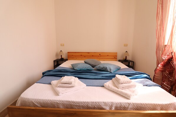 A neatly made bed with blue and white bedding, two pillows, and two bedside lamps.