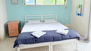 Une chambre à coucher avec un lit, une table de chevet, une fenêtre et un tableau accroché au mur.