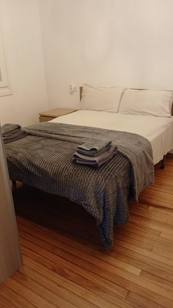 A single bed with a grey blanket and pillows, a wooden floor, and a white wall. - AS NEVEIRAS, TYPICAL GALICIAN RURAL HOUSE (Fixó)