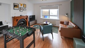 Ein Wohnzimmer mit Tischfußball, Kamin, Sofa und Fernseher.