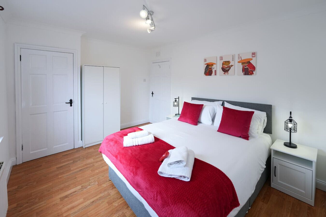 Habitación de hotel ordenada con una cama grande, una mesita de noche y un armario.