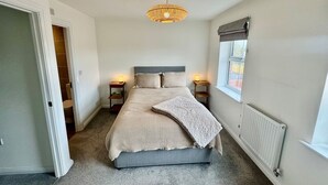 A bedroom with a bed, bedside lamps, a window with a view, and a radiator. - Upper Townhouse, Exeter (Devon)