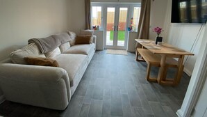 A modern living room with a sofa, a dining table, and a TV. - Upper Townhouse, Exeter (Devon)