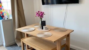 A modern dining area with a wooden table, bench, and a flat-screen TV mounted on the wall. - Upper Townhouse, Exeter (Devon)