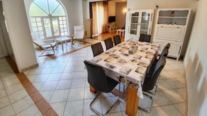 A dining area with a large table, chairs, and a cabinet with glass doors.