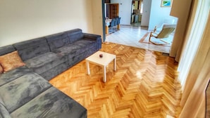 A living room with a sofa, a small table, and a herringbone wooden floor.