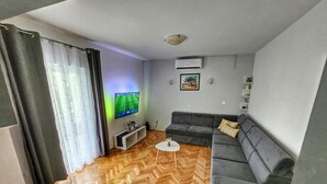 A modern living room with a grey sofa, a small white coffee table, and a herringbone wooden floor.