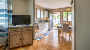 A compact kitchen with a TV, wooden cabinets, and a dining area with a table and chairs.