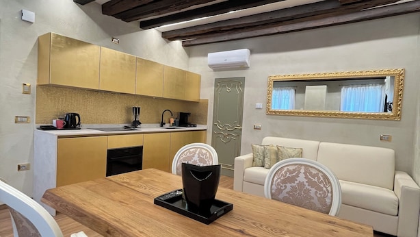 Une cuisine moderne avec des meubles en bois, une table à manger avec des chaises et un coin salon comprenant un canapé et un miroir.