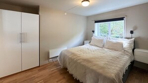 Ein Schlafzimmer mit Bett, Kleiderschrank, Fenster und Deckenleuchte.