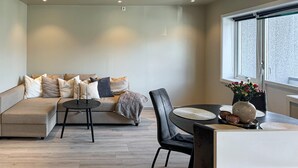 Ein modernes Wohnzimmer mit einer Couch, einem Esstisch mit Stühlen und einem großen Fenster.