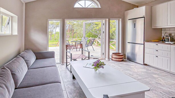 A modern kitchen with a built-in refrigerator, a dining area with a white table and chairs, and a grey sofa. - 2 bedroom awesome home in Visby (Visby)