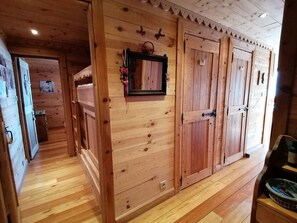 A wooden interior with a hallway leading to a room with a door.