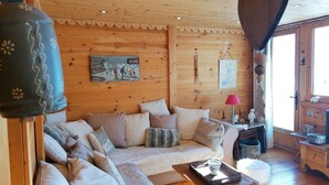 A cozy wooden interior with a sofa, pillows, a table with a tray, and a hanging lamp. - 3-room apartment for 7 people, renovated, sunny balcony (Pra-Loup)