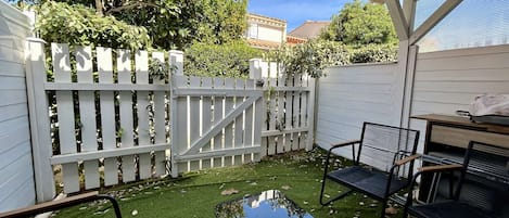 Un patio cubierto con cerca blanca, una mesa y dos sillas.