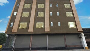 Een meerlaags gebouw met een vlakke gevel, grote ramen met gordijnen en gesloten rolluiken op begane grond.