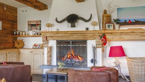 Ein gemütliches Wohnzimmer mit Kamin, Holzbalken und rustikalem Dekor.