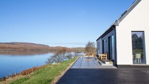 Un bâtiment moderne doté d’un patio donnant sur un lac.
