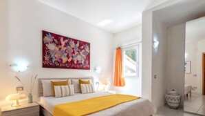 Une chambre à coucher avec un lit, des tables de chevet, une commode, une fenêtre avec des rideaux et un tableau au mur.