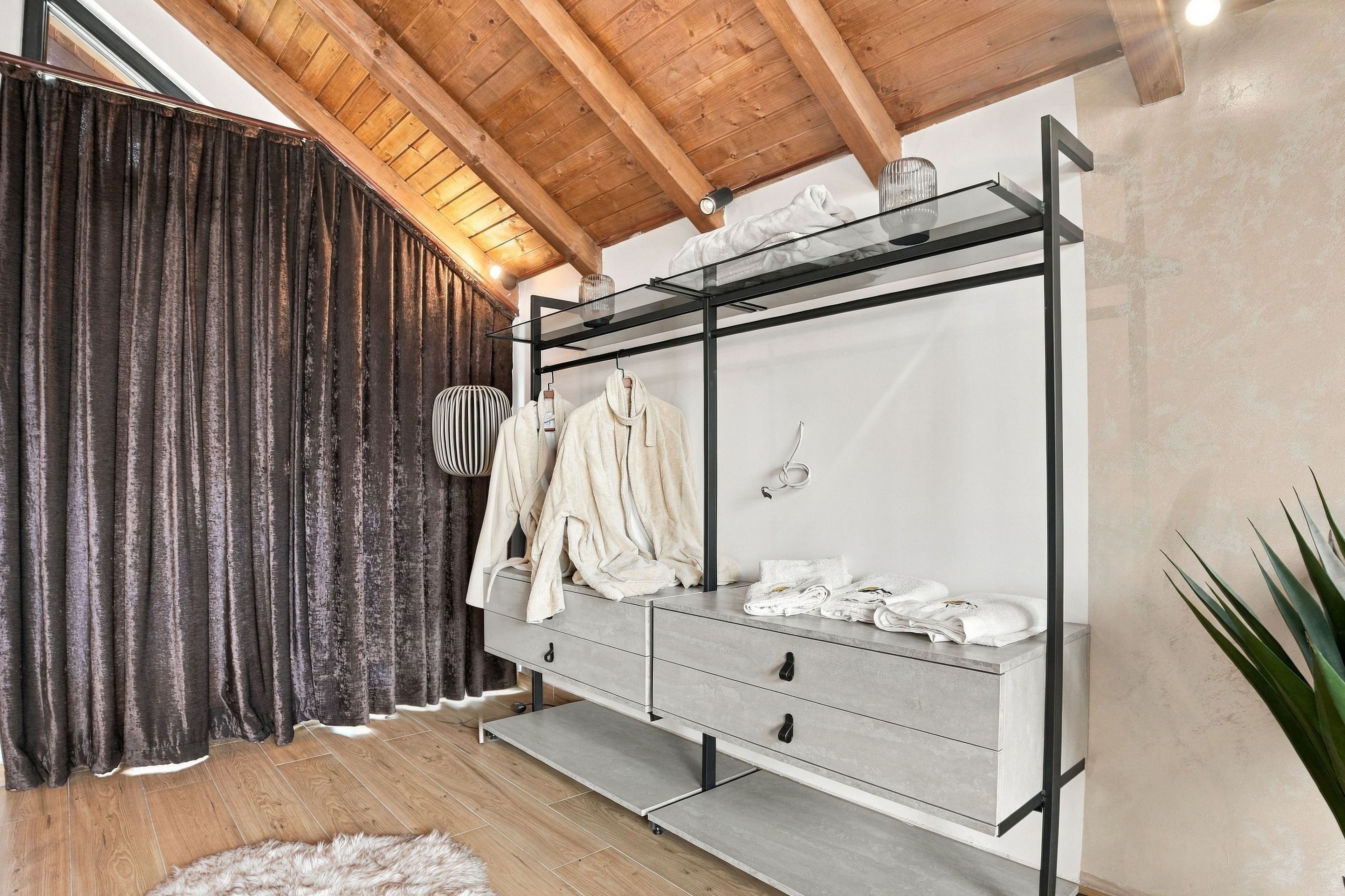 Une chambre moderne avec un plafond en bois, une armoire grise dotée d’une étagère en verre et un tapis moelleux.