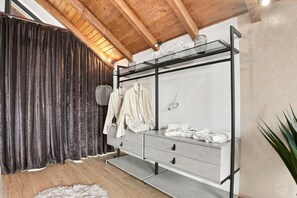Une chambre moderne avec un plafond en bois, une armoire grise dotée d’une étagère en verre et un tapis moelleux.