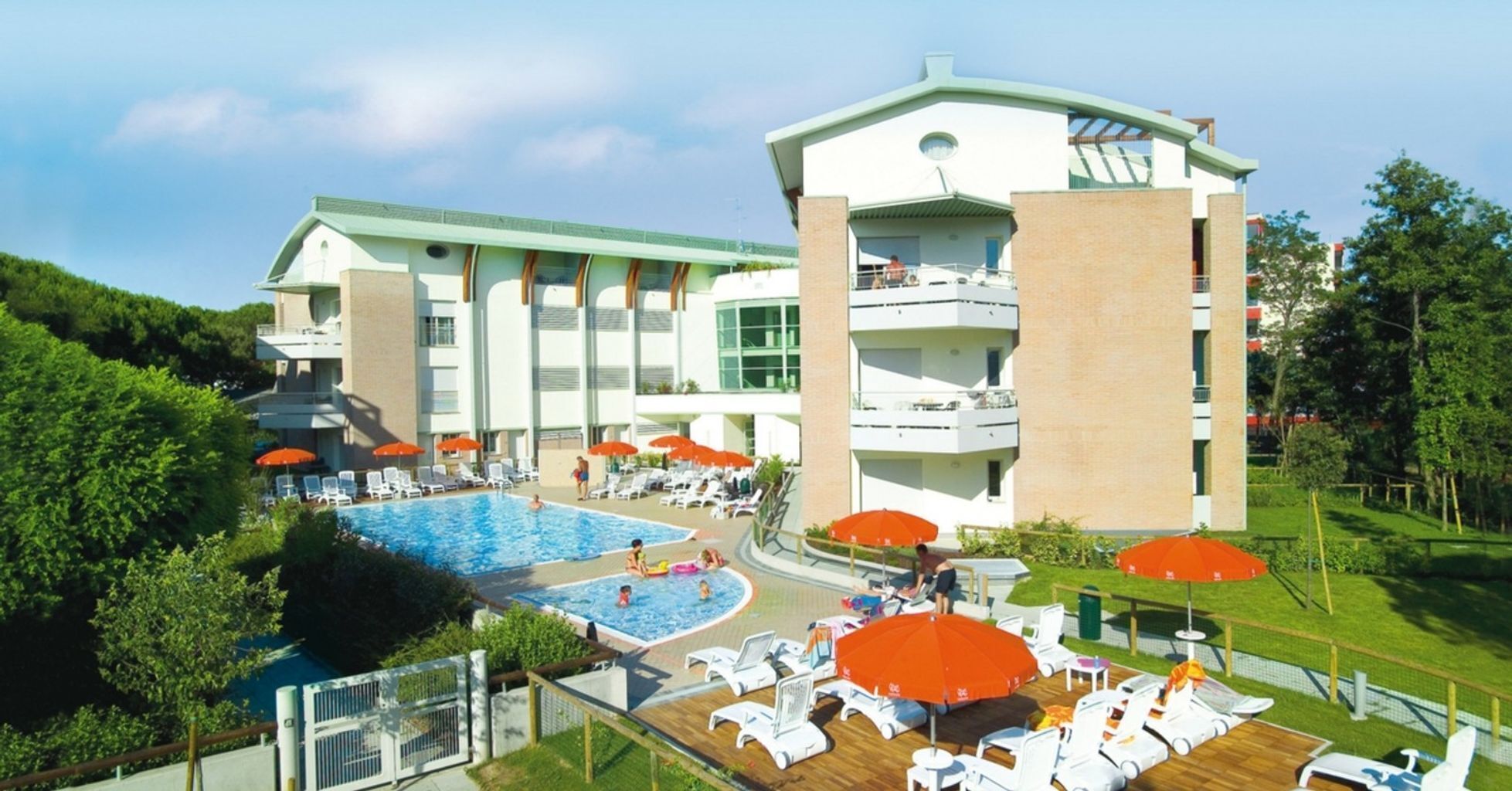 Ein Hotel mit einem großen Schwimmbecken, mehreren Liegestühlen und Sonnenschirmen.