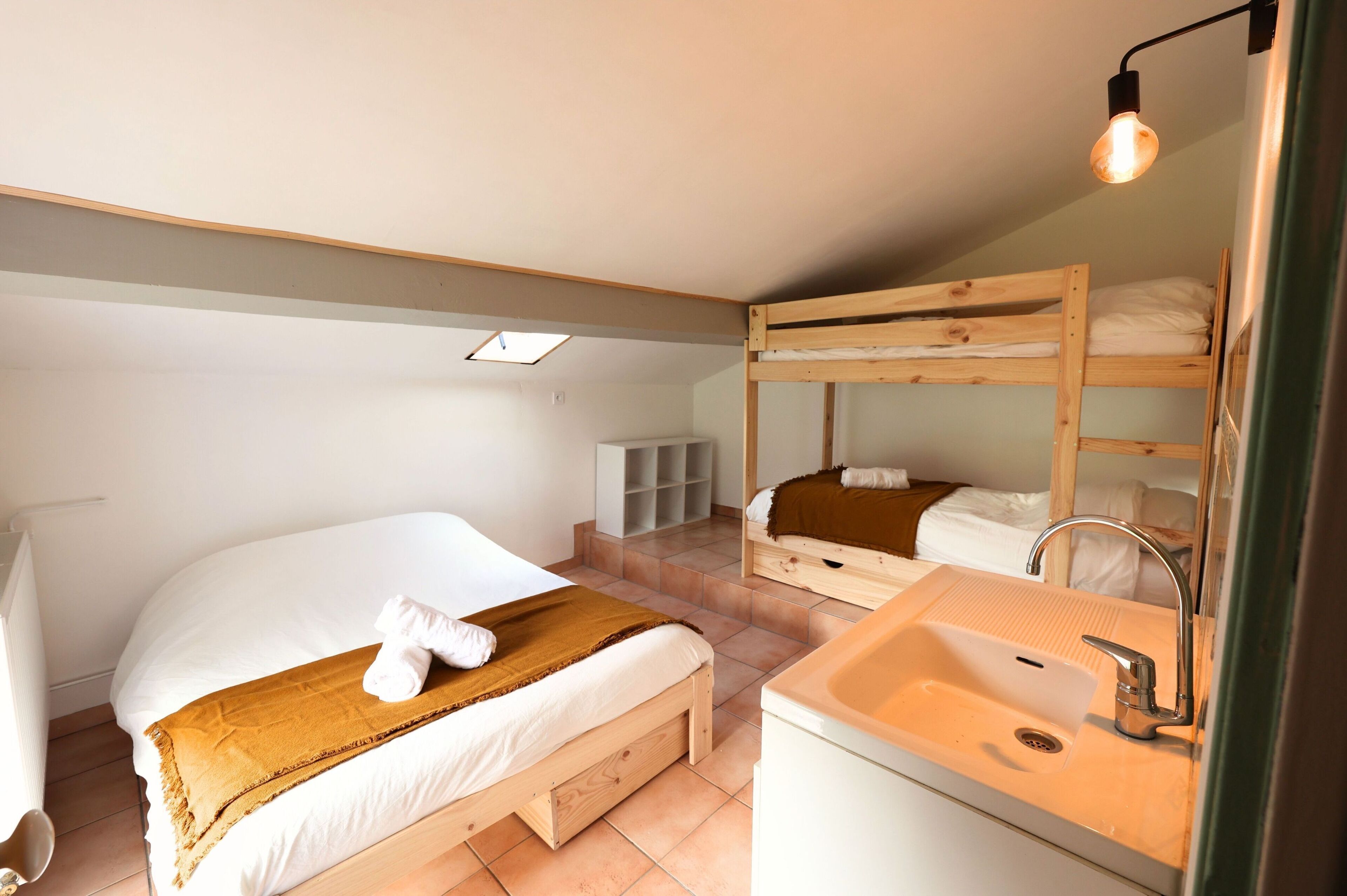 A bedroom with a bunk bed, a single bed, a sink, and a mirror.