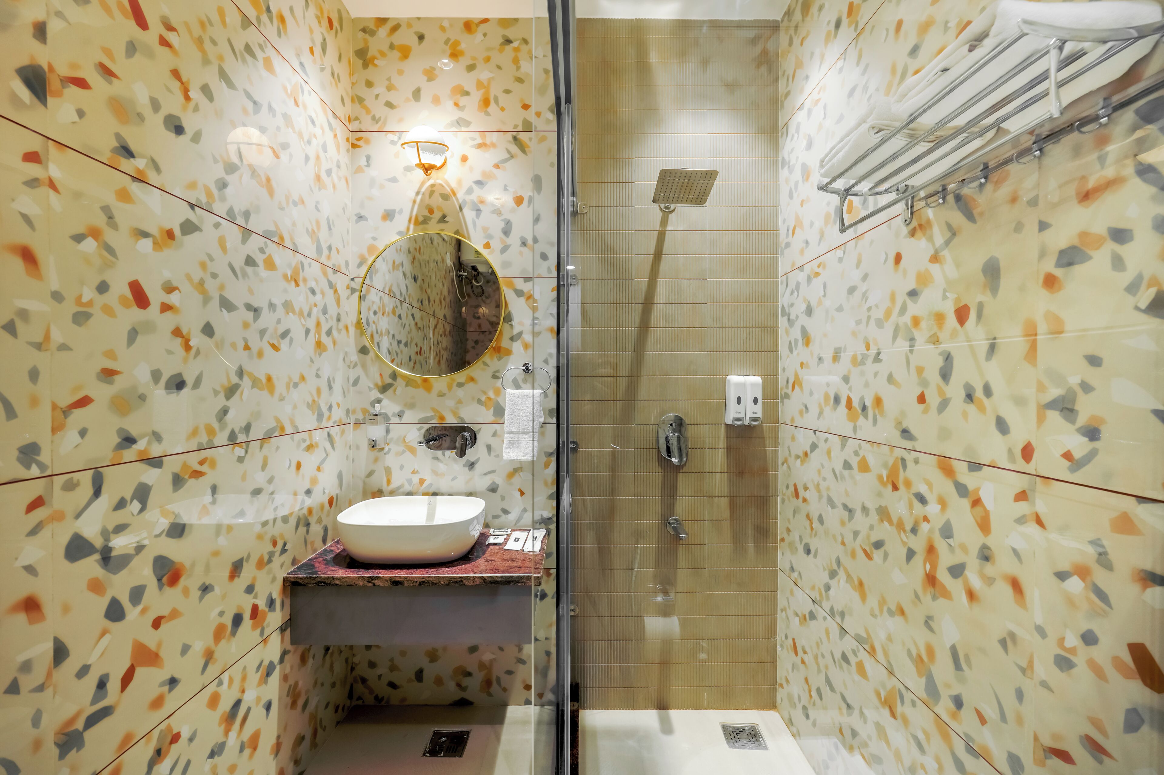A bathroom with a round mirror, a sink, a shower, and a towel rack.