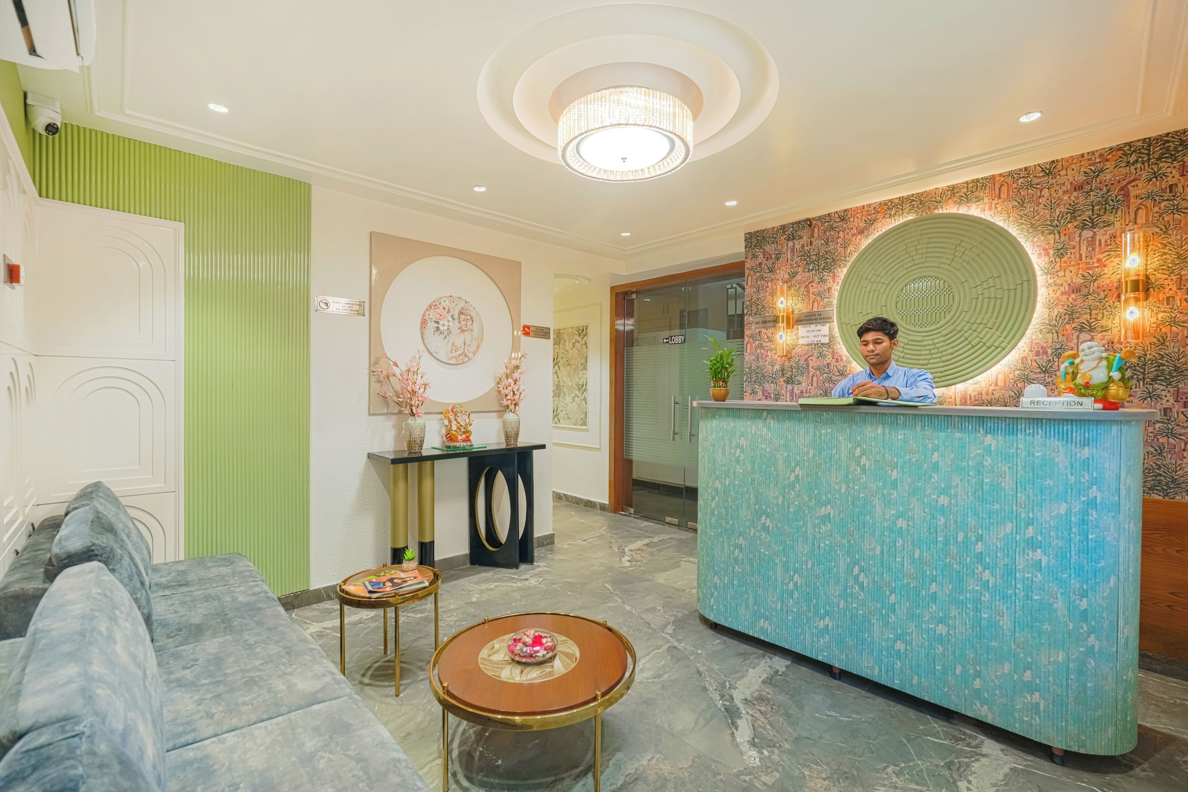 A reception area with a blue counter, a sofa, a small table, and a decorative wall.