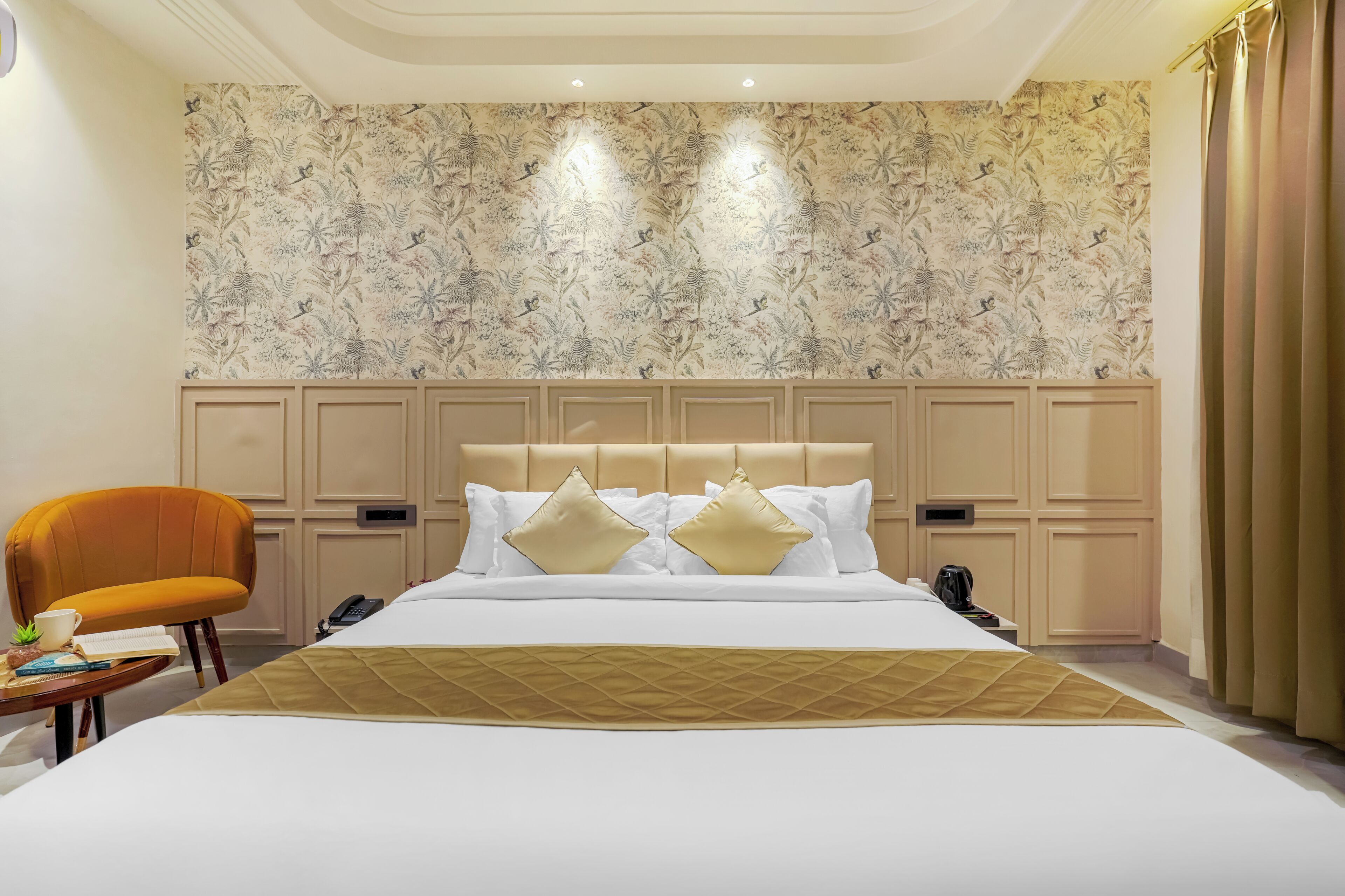 A hotel room with a large bed, a headboard with panels, a desk with a chair, and a telephone.