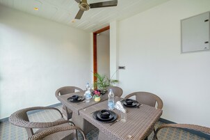 Un comedor con mobiliario de mimbre, ventilador de techo y lámpara fijada a la pared.