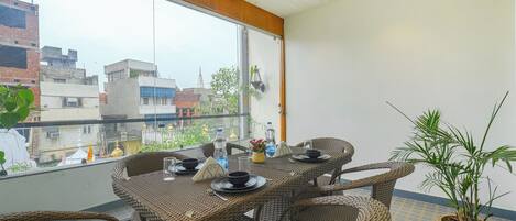 A balcony with wicker furniture, a potted plant, and a view of buildings.