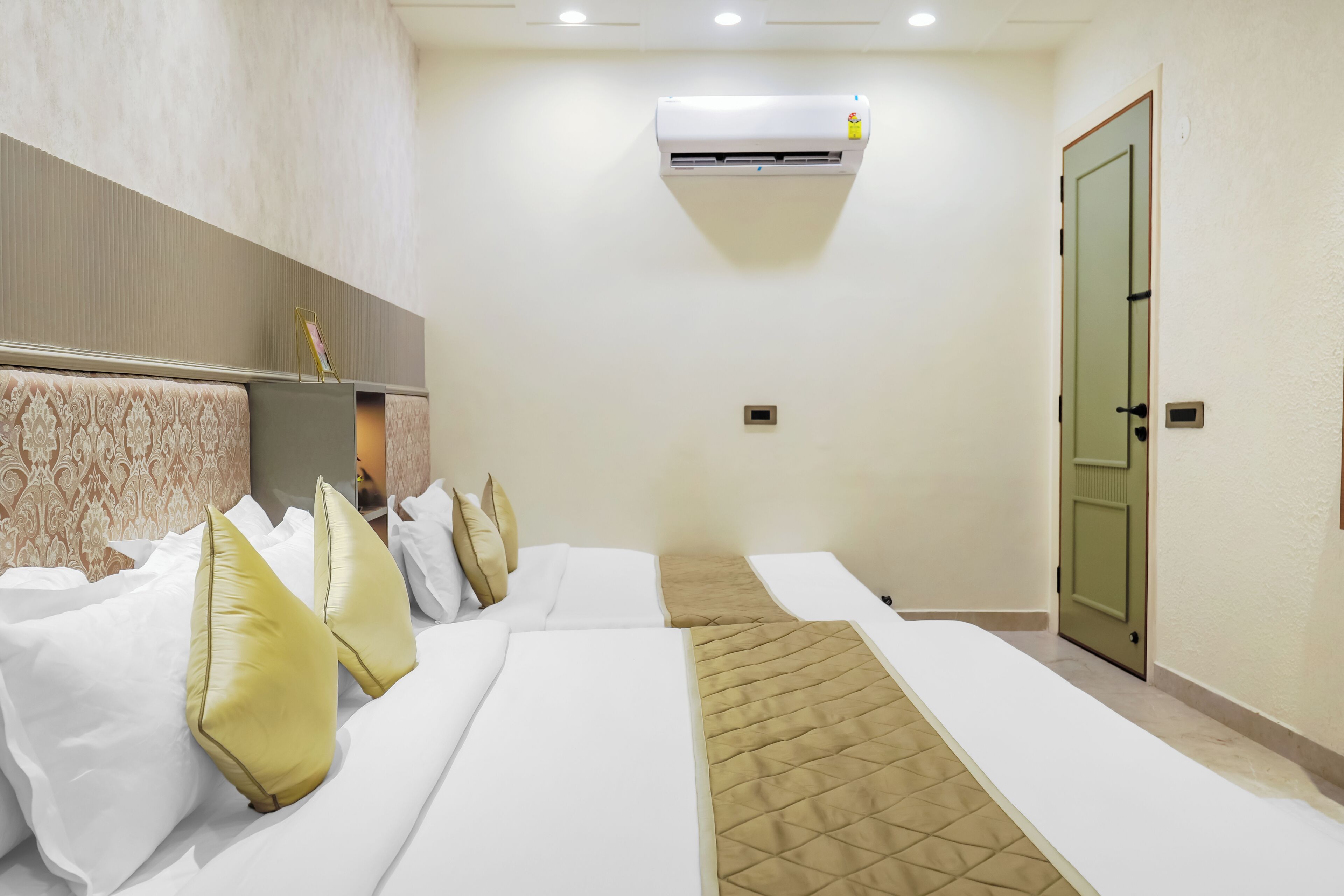 Une chambre d’hôtel avec deux lits, un climatiseur fixé au mur et une porte.