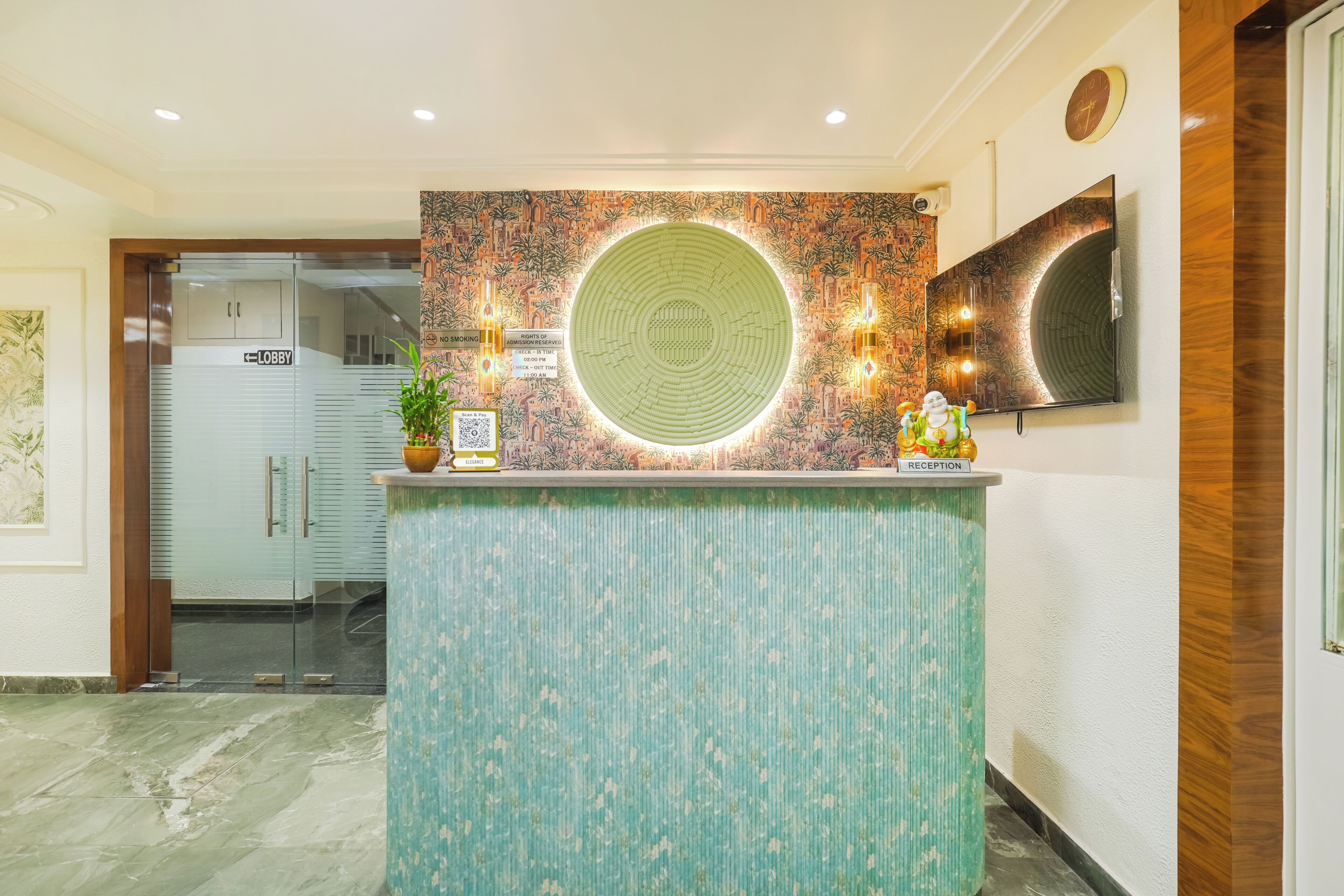 A reception desk with a patterned wall, a clock, and a television.